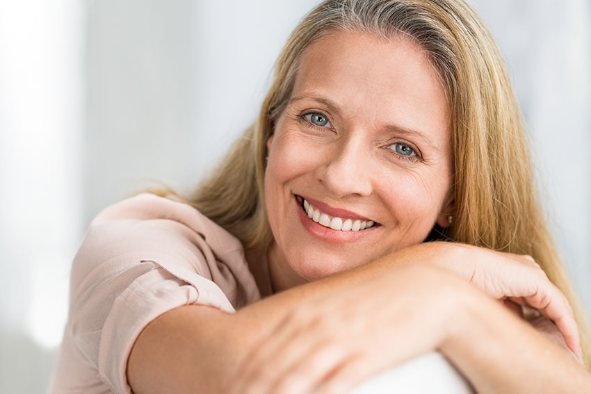 pretty mature woman leaning over her couch, smiling