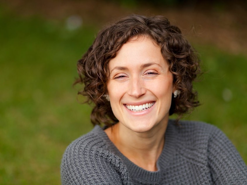 woman with curly dark hair smiling with teeth