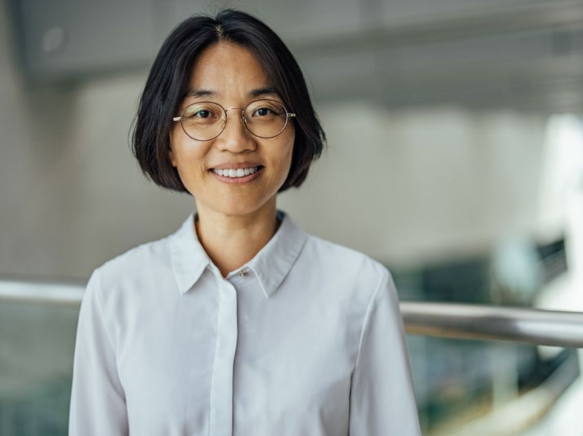 Woman with dark hair and glasses smiling